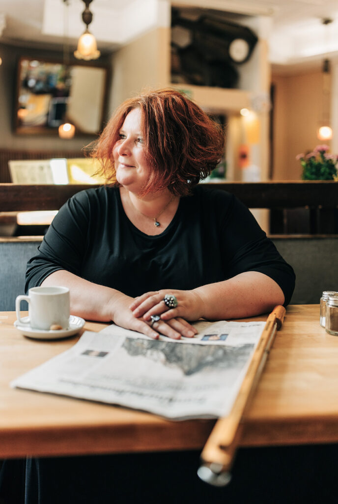 Portrait Heidi Sekulla blickt aus dem Fenster, vor ihr liegt eine Zeitung